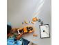 Kind bouwt een oranje speelgoedauto met onderdelen op tafel, instructies volgend op een tablet.