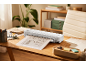 Een witte lamineermachine op een houten bureau die de blauwdruk van een huis lamineert.