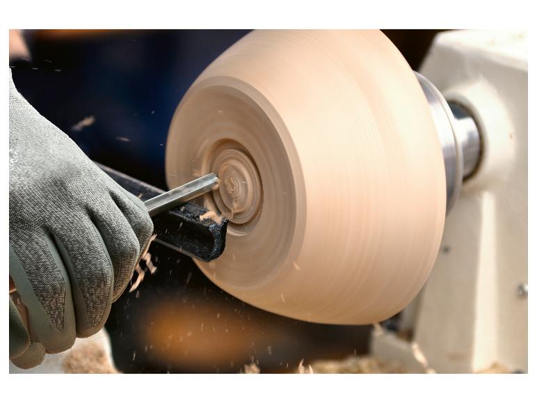 Een houten kom wordt op een draaibank bewerkt met een beitel.