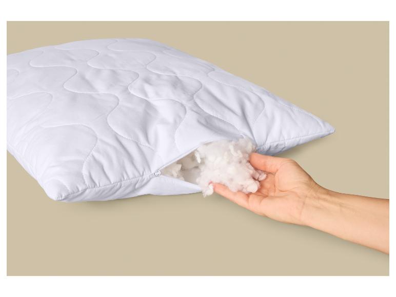 Wit gewatteerd kussen met rits, hand houdt pluizige vulling vast