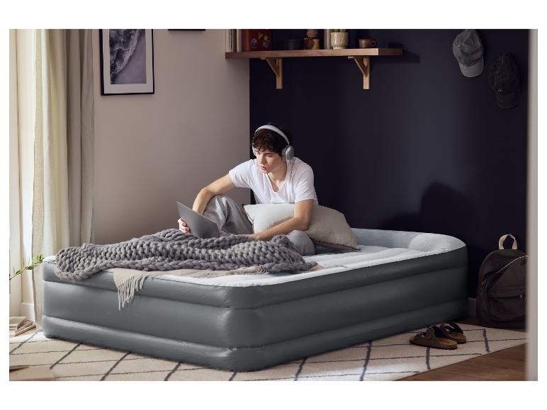 Jonge man zit op een LIVARNO® Premium luchtbed met een laptop en koptelefoon.