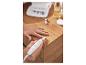 Persoon gebruikt elektrische manicureset met accessoires op een houten tafel.