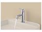Chromen wastafelkraan met stromend water in een beige keramische wasbak.