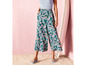 Een vrouw draagt een broek met bloemenprint en slippers.