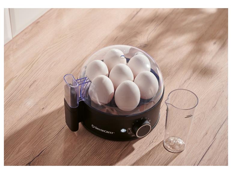 SilverCrest eierkoker met zeven eieren en maatbeker op een houten ondergrond.