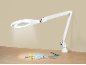 Witte vergrootlamp verlicht naaiartikelen op een houten tafel.