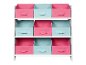 Wit houten speelgoedopbergmeubel met roze en blauwe stofbakken.