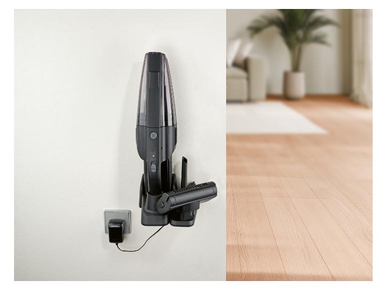 Zwarte handstofzuiger aan de muur met oplader in een modern interieur.