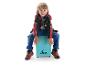 Een lachende jongen zit op een turquoise cajon, met zijn handen op het oppervlak.