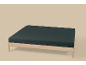 Licht houten eenpersoonsbed met donker matras op een beige achtergrond.