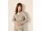 Vrouw in een beige gebreide trui en broek, met gekruiste handen.