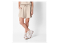 Beige shorts en witte platform sneakers.