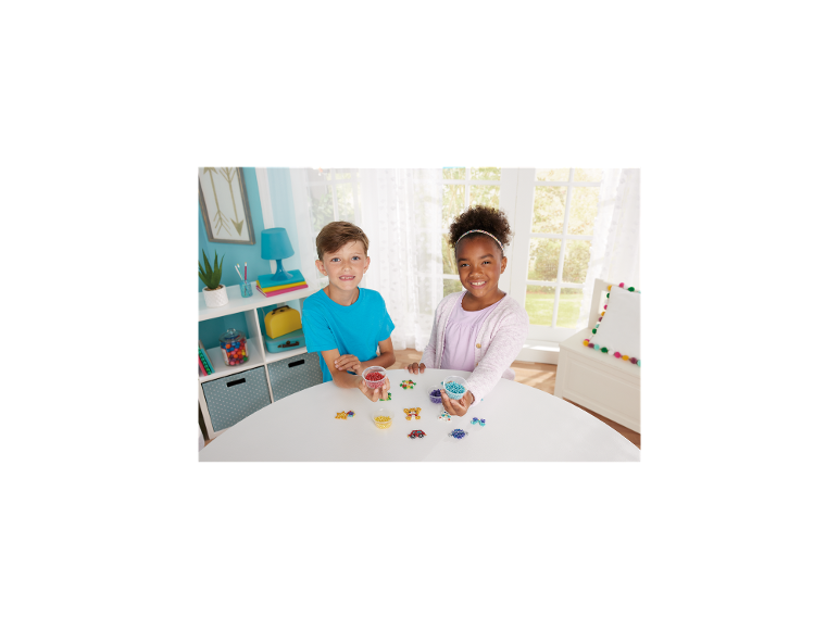 Twee kinderen knutselen vrolijk met kleurrijke kralen aan een witte tafel.