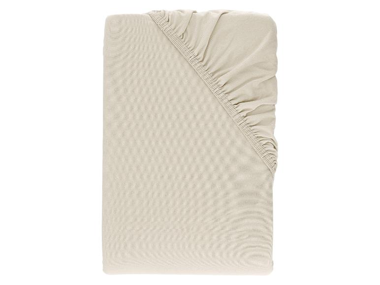 Lichtbeige hoeslaken, opgevouwen met de elastische hoek zichtbaar.