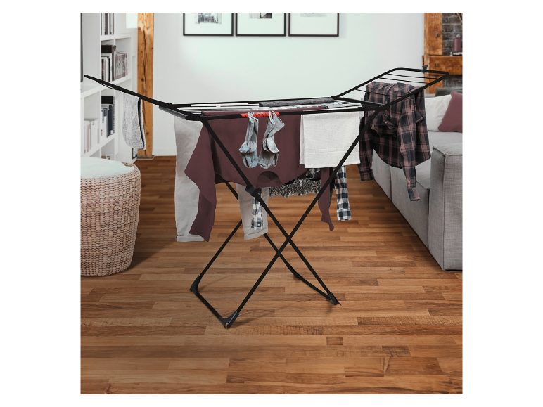 Een zwarte inklapbare wasdroger op een houten vloer.