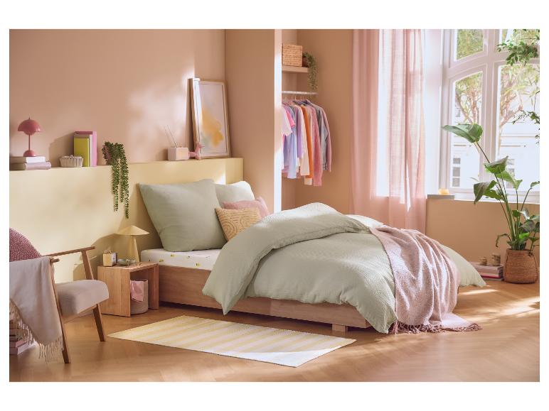 Slaapkamer met bed, open kledingkast, planten en decoratie in pastelkleuren.