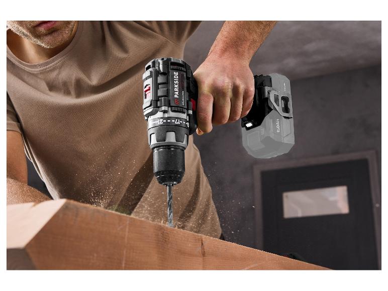 Accuboormachine boort in een stuk hout, met rondvliegende houtsnippers.