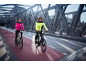 Twee mensen in reflecterende jassen fietsen op een brug met een fietspad.