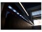 LED-stripverlichting onder een plank, met een warme lichtstrip erboven en een raam op de achtergrond.
