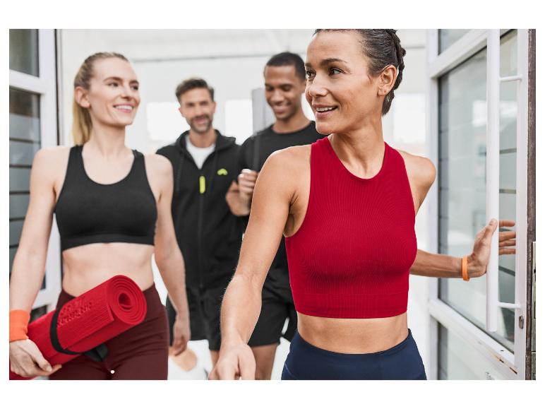 Jonge vrouwelijke atleten verlaten een sportschool met yogamatten.