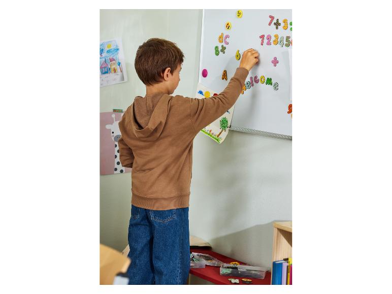 Kind plaatst kleurrijke magnetische letters en cijfers op een whiteboard.