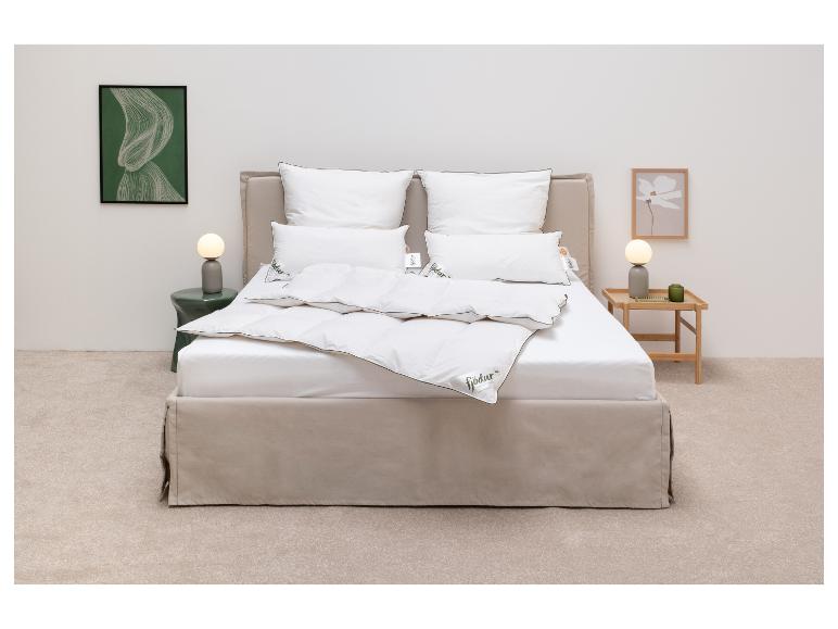 Slaapkamer met een bed met wit beddengoed en Fjödur-dekbedden, geflankeerd door nachtkastjes met lampen.