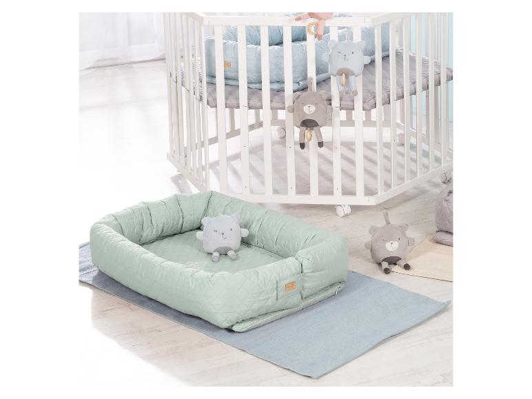 Wit houten ledikant met wielen en een mintgroen babynestje met berenspeelgoed.