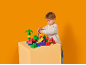 Een jonge jongen speelt met kleurrijke bouwstenen op een tafel tegen een oranje achtergrond.