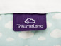 Een paars label met de tekst 'Träumeland' op een lichtblauw beddengoed met witte wolken.