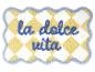 Geel-wit geruite badmat met blauwe tekst 'la dolce vita'.