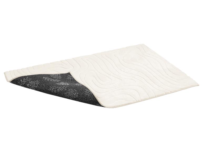 Crèmekleurige badmat met golvend patroon en antislip onderkant met bloemmotief.