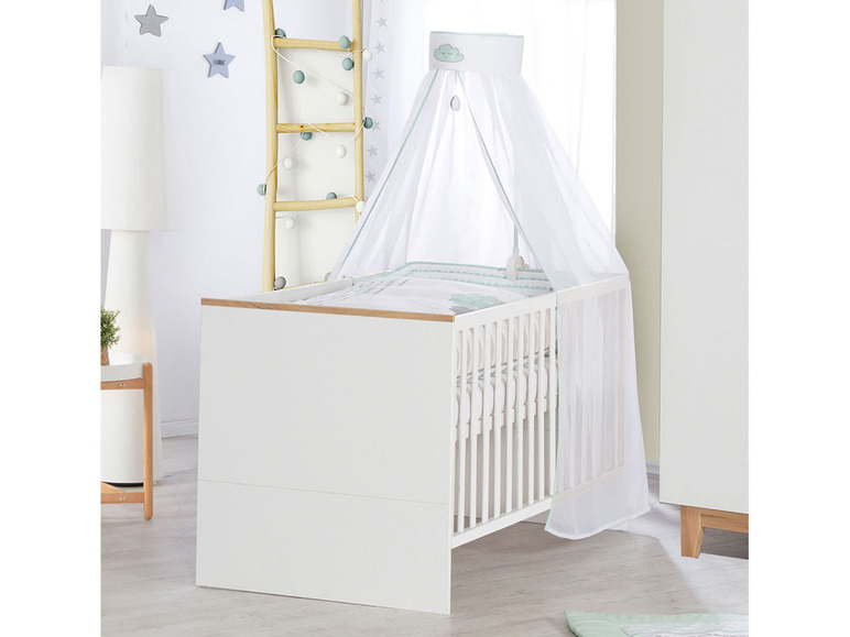 Een witte babywieg met een hemel en een groene wolk print.