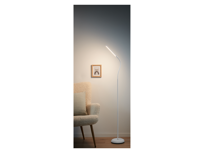 Moderne witte LED staande lamp naast een fauteuil.