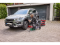 Man verwisselt autobanden, met behulp van een autokrik en een elektrische slagmoersleutel.