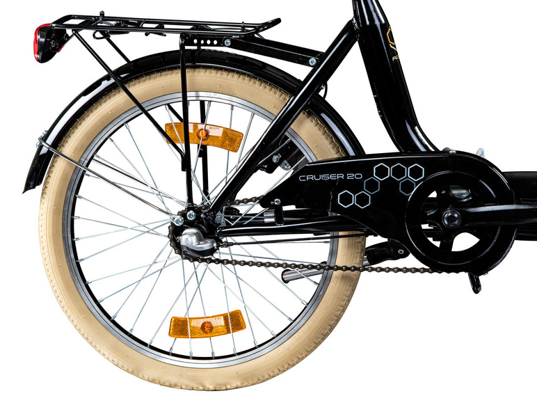 Achterwiel van een zwarte cruiserfiets met crèmekleurige banden.