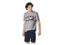 Man in een grijs T-shirt met stripfiguurprint en een marineblauwe korte broek.