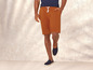 Man draagt ​​oranje shorts en blauwe sneakers.
