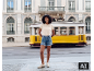 Vrouw in beige opengewerkt T-shirt en denim short voor een gele tram.