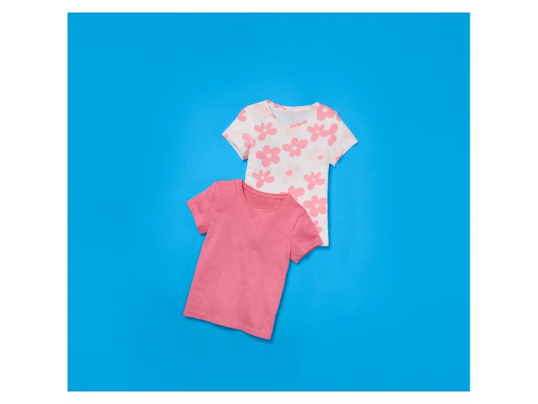 Twee kinder-T-shirts, één roze en één wit met roze bloemen, op een blauwe achtergrond.