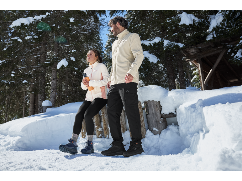 Man en vrouw in winterkleding en schoenen in een besneeuwd bos.