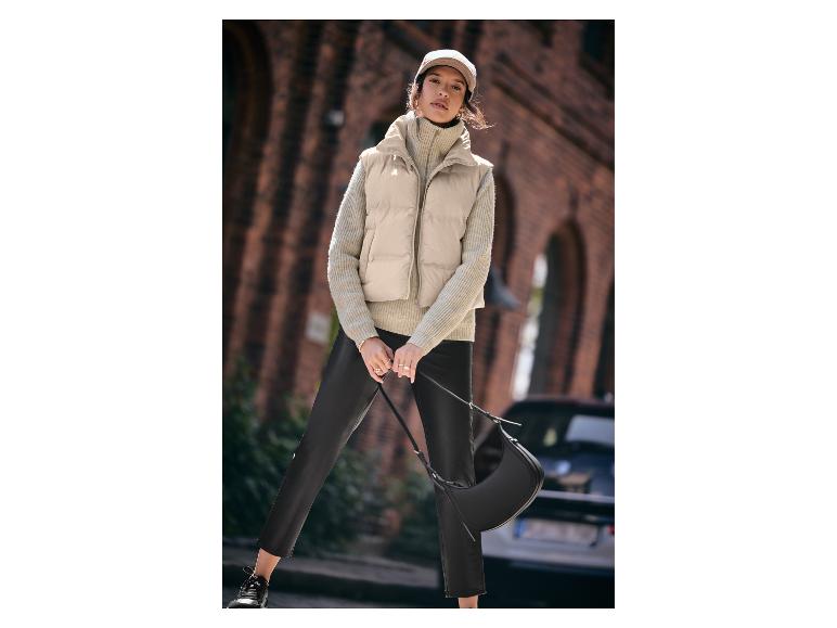 Vrouw met beige vest, gebreide trui en leren broek.