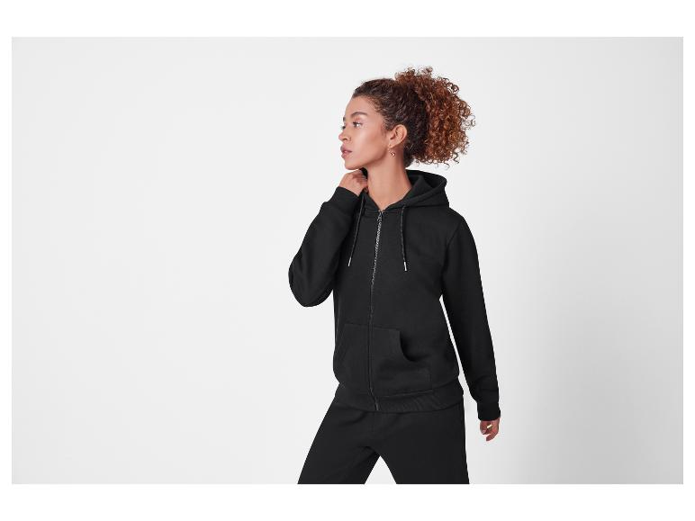 Vrouw in een zwarte hoodie met rits en bijpassende joggingbroek.