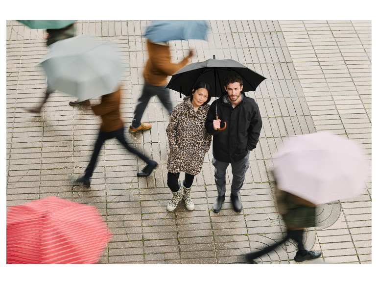 Een stel staat onder een paraplu op een regenachtige straat.