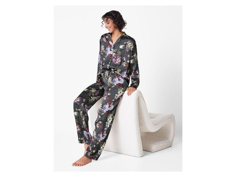 Lachende vrouw in satijnen pyjama met bloemenprint, zittend op een witte stoel.