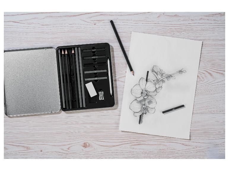 Schetsset met houtskoolpotloden en een orchideeënschets op een houten tafel.