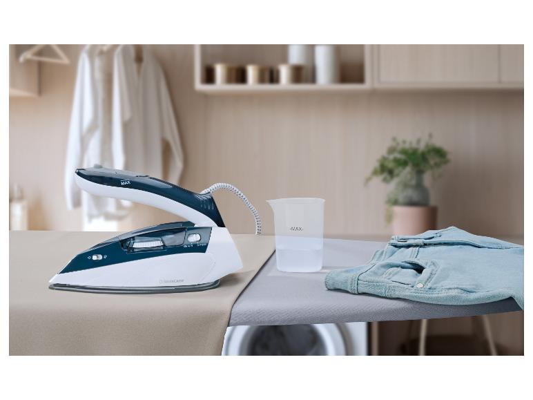 Stoomstrijkijzer met maatbeker en jeans op een strijkplank in een wasruimte.