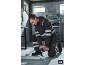 Man in reflecterende werkkleding met gereedschap werkt aan metalen constructies.