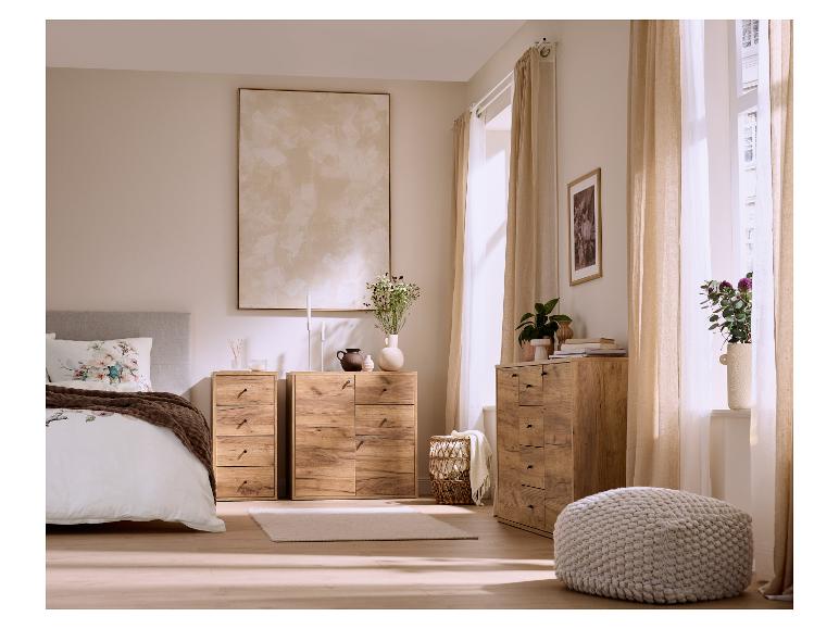 Slaapkamer met houten ladekasten, een bed met bloemenbeddengoed en lichte gordijnen.