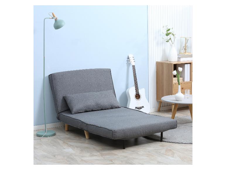 Grijze uitklapbare bank met kussen in een woonkamer met lamp en gitaar.