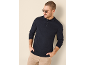 Man in donkerblauwe polo met lange mouwen en beige broek, zonnebril.